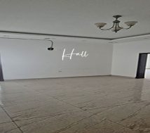 A wide-angle view of a large, empty office hall with two doorways leading to other rooms. A 2 rooms office 100 m2 in the lowest rent of BHD 200 per month at Hidd, Bahrain.
