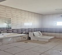 A small, empty bathroom with a white sink, a toilet, and tiled walls.